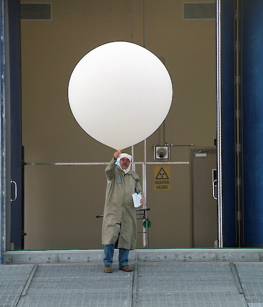 man in protective gear with large white balloon and ozone sonde