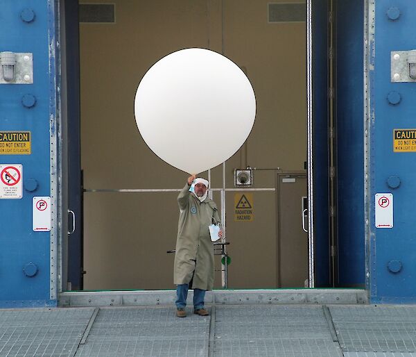 man in protective gear with large white balloon and ozone sonde