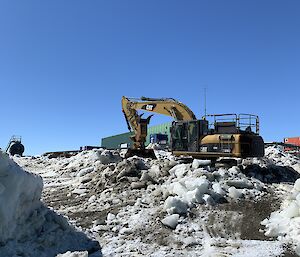 Excavator clearing a road of snow and gravel