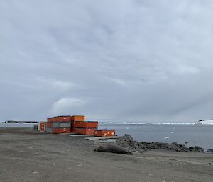 Containers sitting on the shore line.  Bergy bits visible in the sea