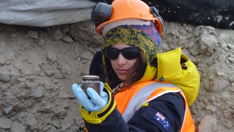 Woman in safety gear holding a frozen soil sample.