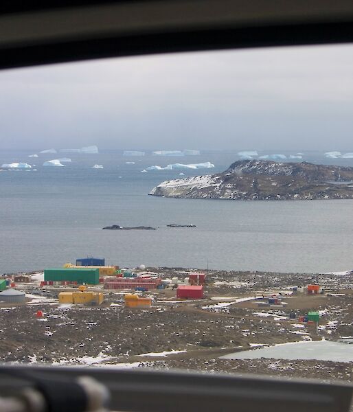 coloured buildings of an Antarctica station with sea and ice bergs behind