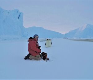 woman in Antarctica with penguins in background and ice cliffs