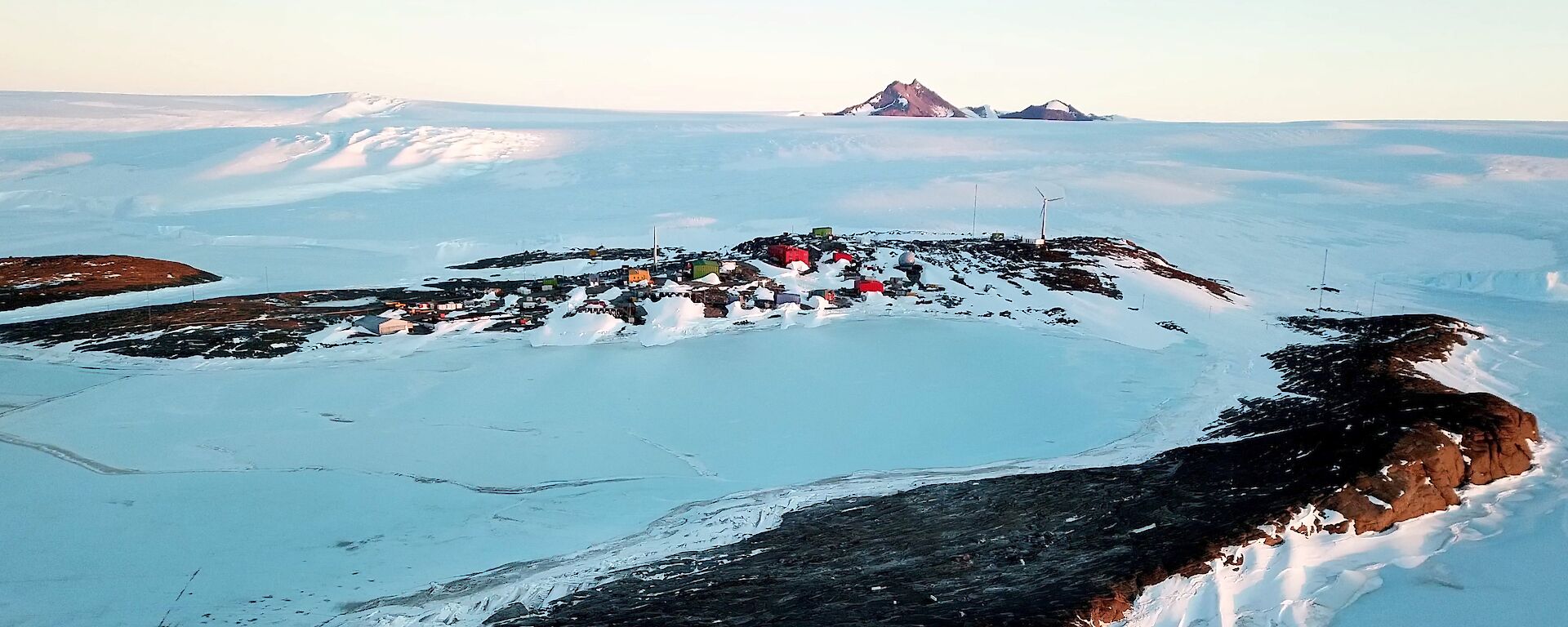 Antarctic research station from the air with mountain in background