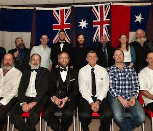 The expeditioners in a staged formal group photo with international flags in the background