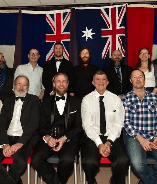 The expeditioners in a staged formal group photo with international flags in the background