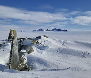 The remains of a plane half buried in a snowy landscape