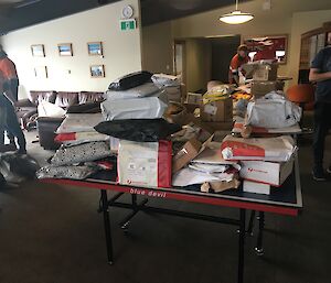 A large pile of mail sitting on a table with expeditioners standing around