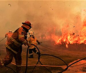 Firefighters in the midst of fighting a raging fire.