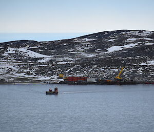 Looking out across a bay, in the middle of which sits a barge driving a load of cargo to shore