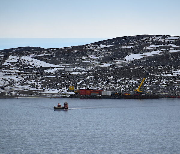 Looking out across a bay, in the middle of which sits a barge driving a load of cargo to shore