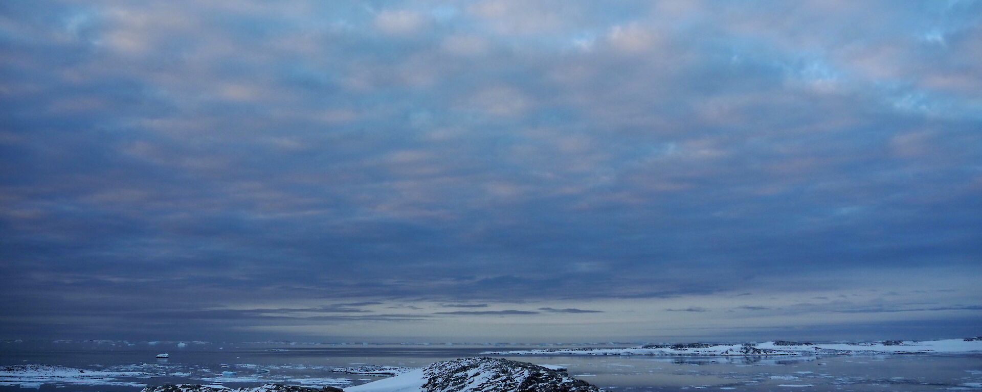 A landscape shot looking across the snow covered ground to the icy water of Newcomb Bay