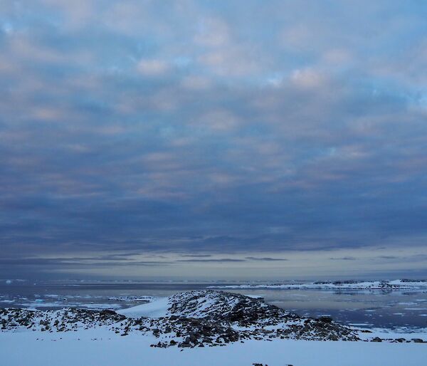 A landscape shot looking across the snow covered ground to the icy water of Newcomb Bay