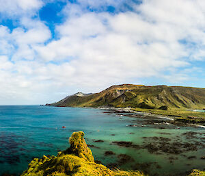A panoramic shot of Macquarie Island looking across the isthmus.  A resupply ship is visible of shore on one side in beautiful turquoise water.
