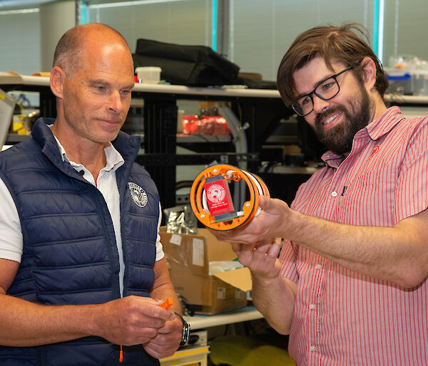 Two people looking at a piece of electronic equipment.