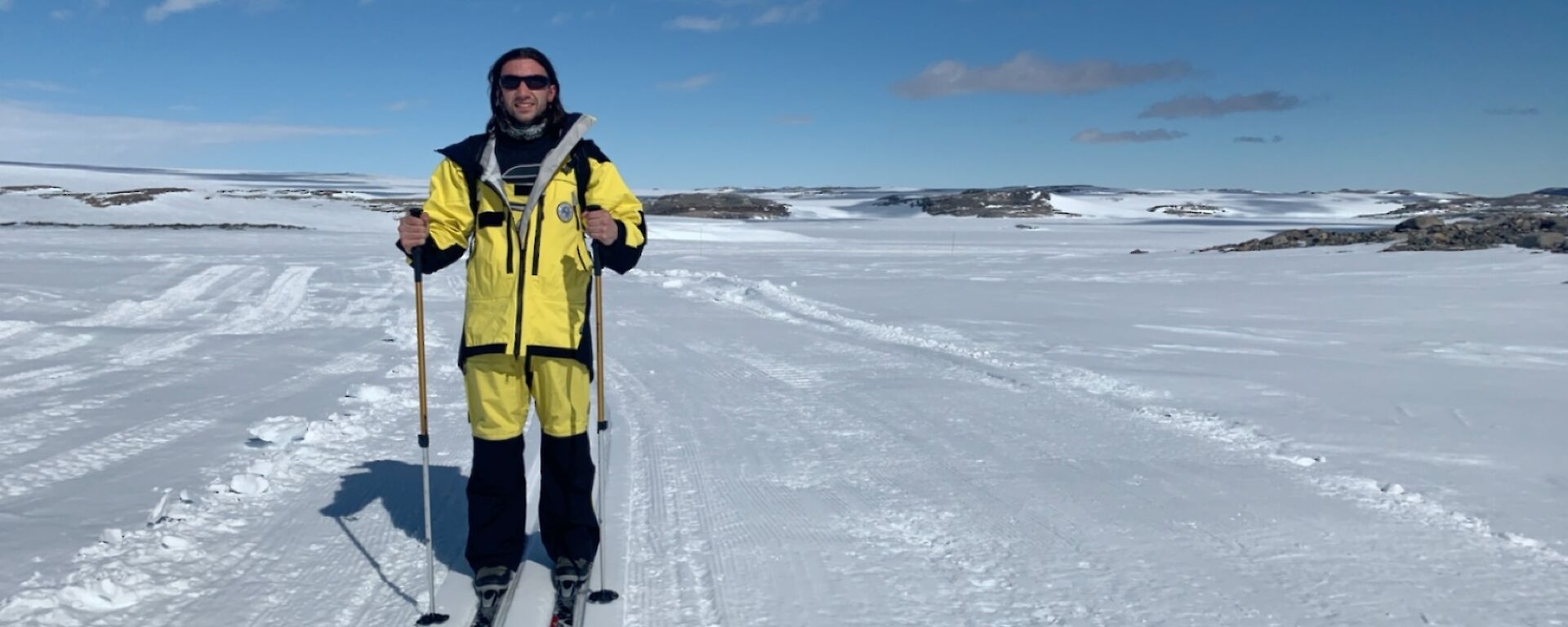 An expeditioner wearing yellow cold weather suit on skis in the snow