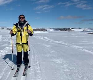 An expeditioner wearing yellow cold weather suit on skis in the snow