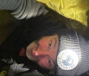 A selfie of a man with a beanie and warm clothing on from inside a swag