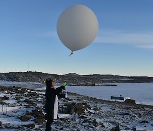 A man in a penguin suit releases a giant weather balloon in to the atmosphere