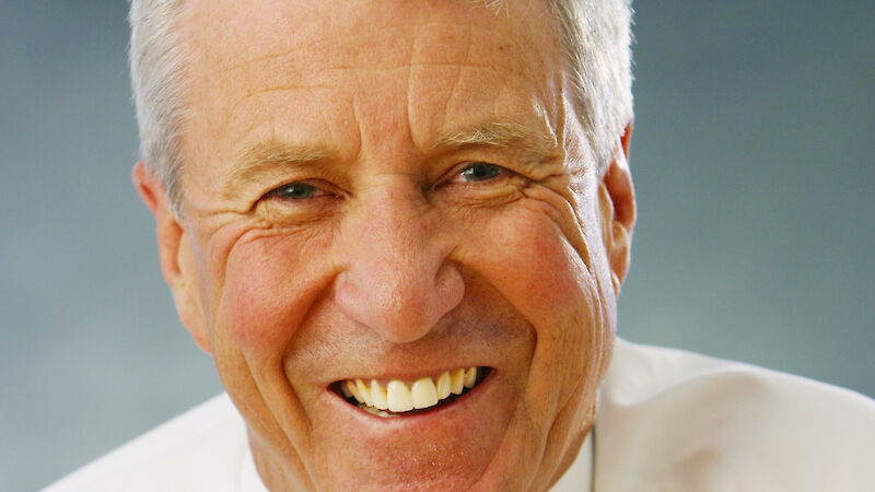 A portrait photo of a white man with grey hair wearing a shirt and tie.