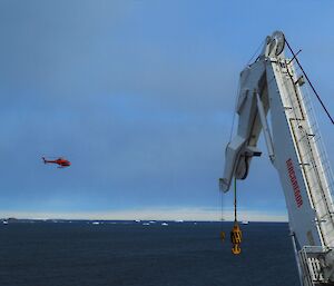 Crane in the foreground with helicopter, small in the background