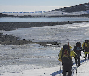 Four expeditioners walk in a line along the ice