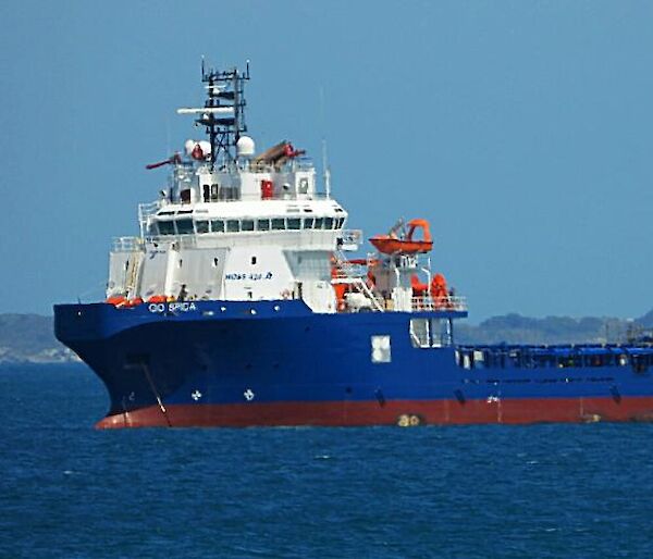 A large blue and white tug boat in a calm ocean.