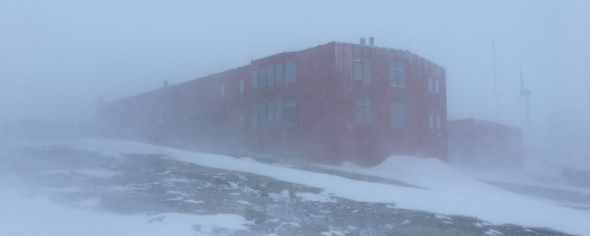 Large red building in the distance barely visible due to blowing snow.