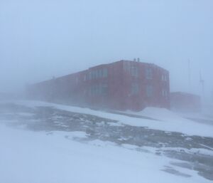 Large red building in the distance barely visible due to blowing snow.