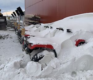 A row of quad bikes covered in snow