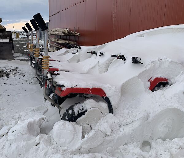 A row of quad bikes covered in snow