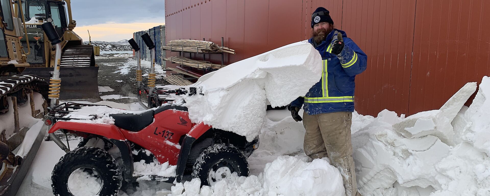 A man helps clear snow from a quad bike