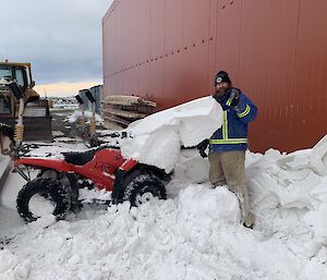 A man helps clear snow from a quad bike