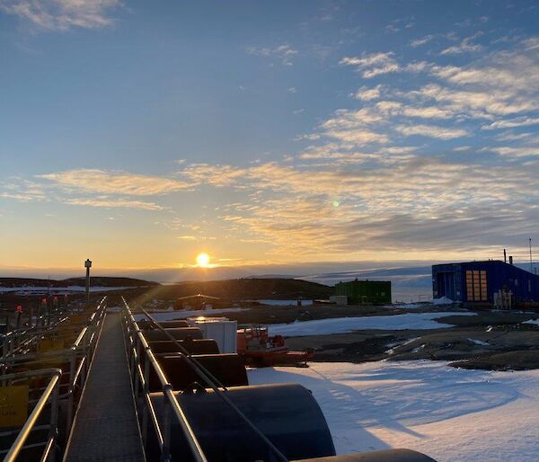 A picture of a sunrise while standing on the steel walkway on top of the station fuel tanks.