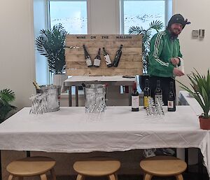 A table covered in white cloth is set up as a make shift bar.  Glasses and sample bottles of wine, beer and champagne can be seen on the table.