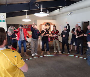 A group of people playing two-up with winners hands raised in the air