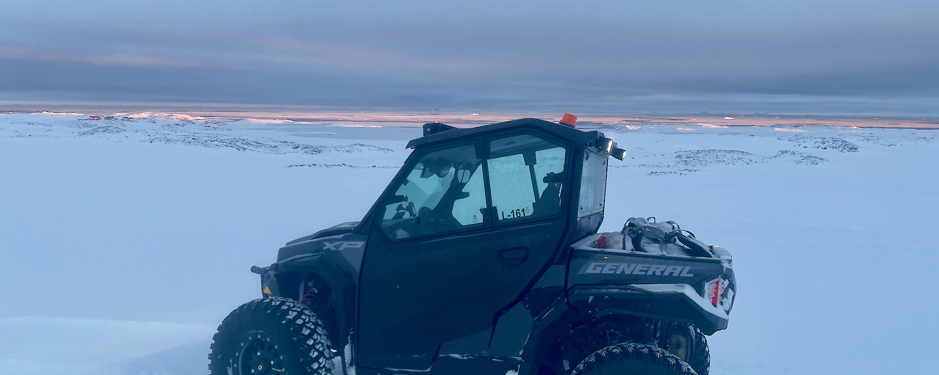 A small quad like vehicle parked in the snow