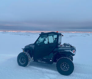 A small quad like vehicle parked in the snow