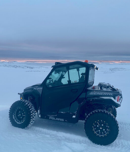 A small quad like vehicle parked in the snow