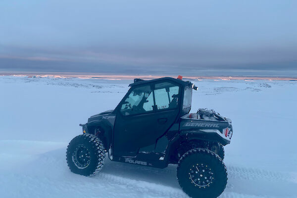 A small quad like vehicle parked in the snow