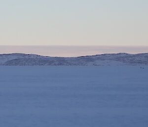 One Emperor Penguin closer to camera on left; the others visible only as as small dots on the right