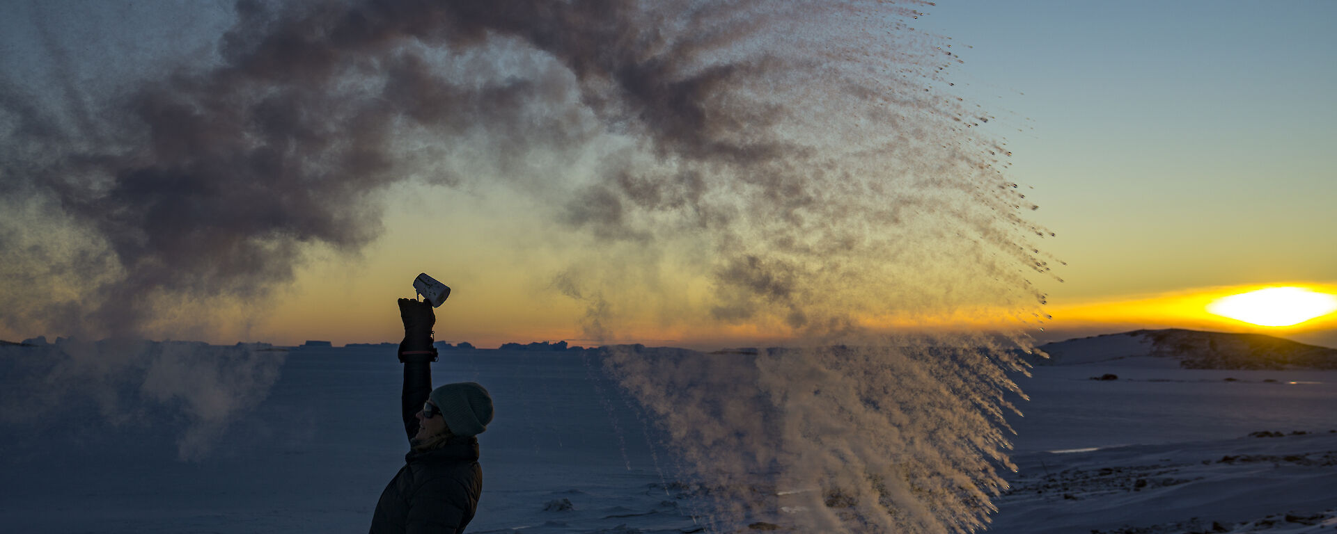 A woman stands in a wave of frozen water against a sunset