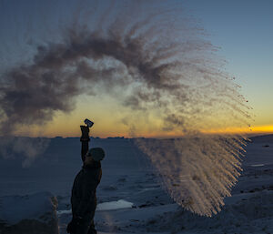 A woman stands in a wave of frozen water against a sunset