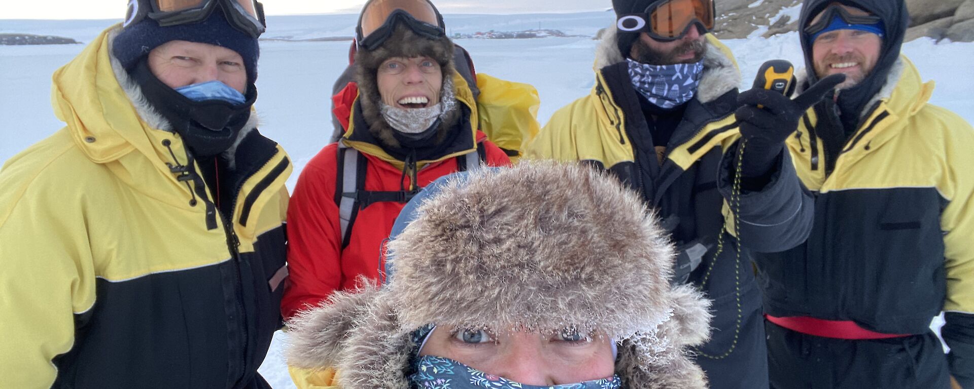 Five expeditioners dressed in their winter clothing gathered for a group photo.