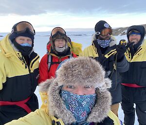 Five expeditioners dressed in their winter clothing gathered for a group photo.