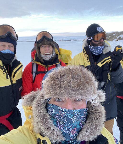 Five expeditioners dressed in their winter clothing gathered for a group photo.