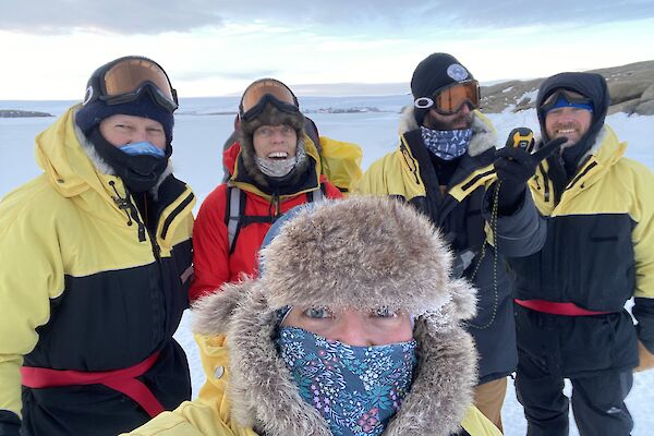 Five expeditioners dressed in their winter clothing gathered for a group photo.