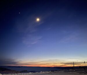 A dark blue and orange sky with the sun high in the sky