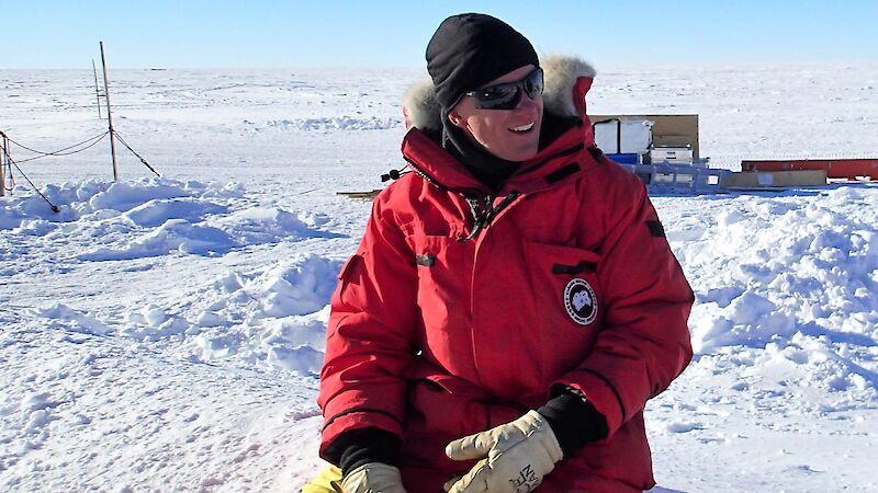 Jason Roberts sits in the snow with warm weather gear and gloves.