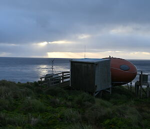 A dark moody image looking out to see past the silhouette of a couple of huts